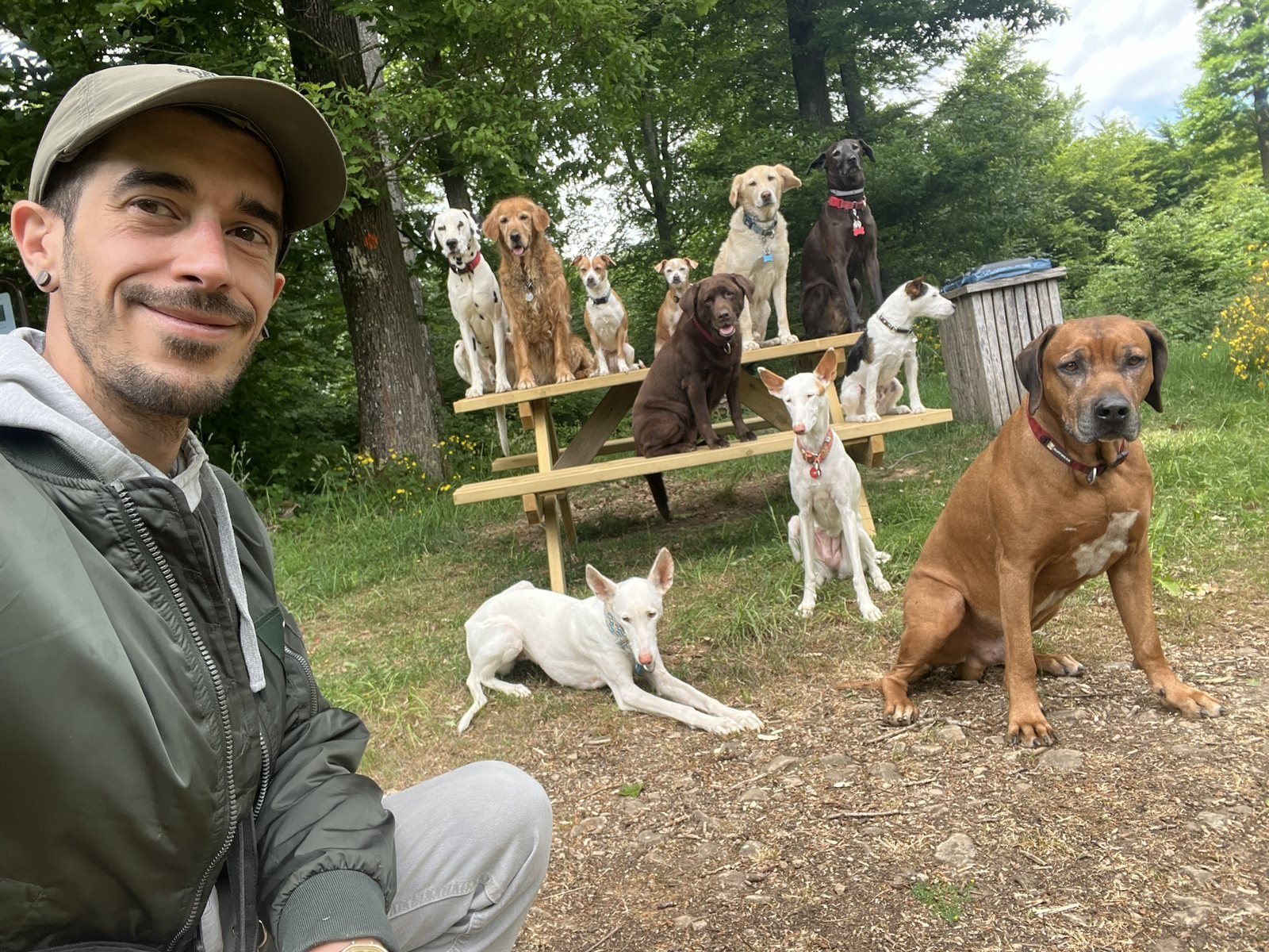 Gabriel Quiaios assis en forêt avec un groupe de chiens